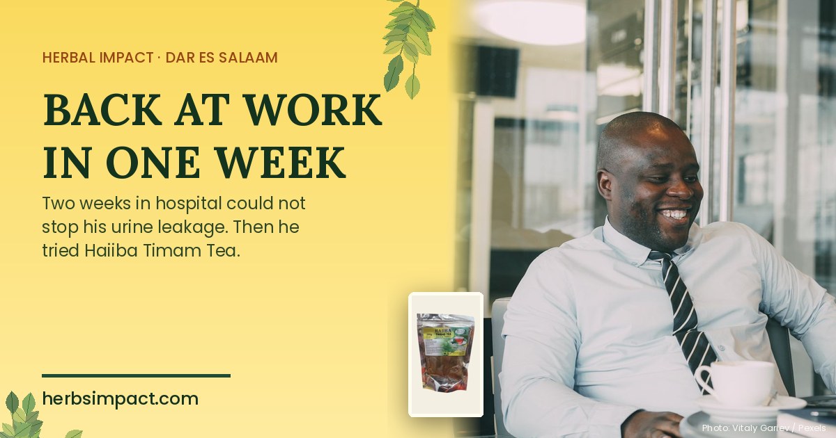 Smiling man back at work in an office with a cup of tea beside a packet of Haiiba Timam Tea, Herbal Impact Dar es Salaam