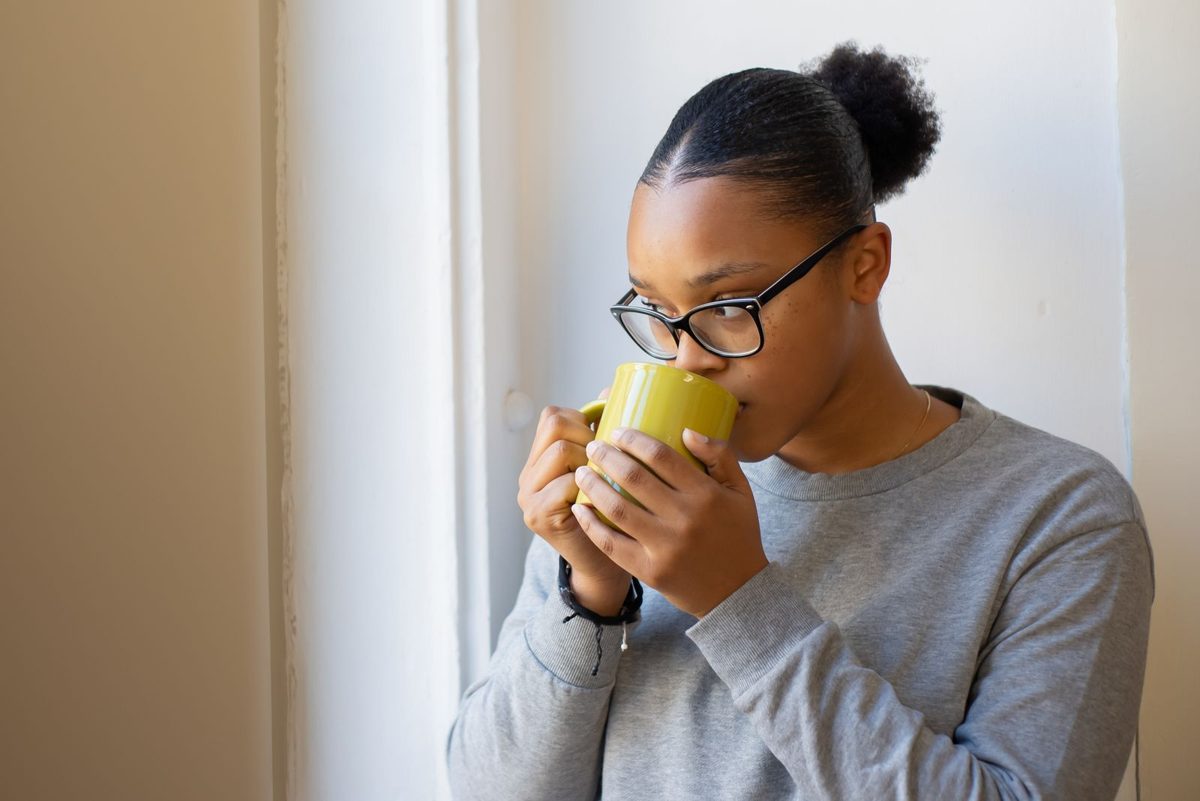 Woman drinking herbal tea from a yellow mug