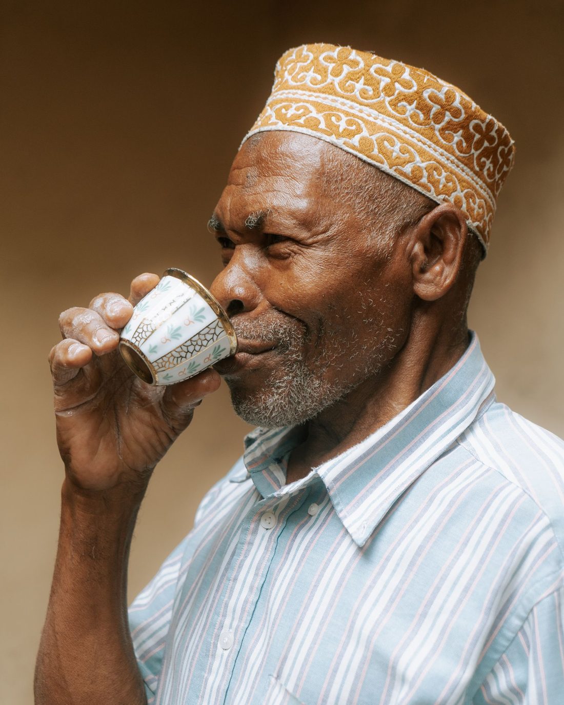 Elderly man in Zanzibar drinking tea from a small cup
