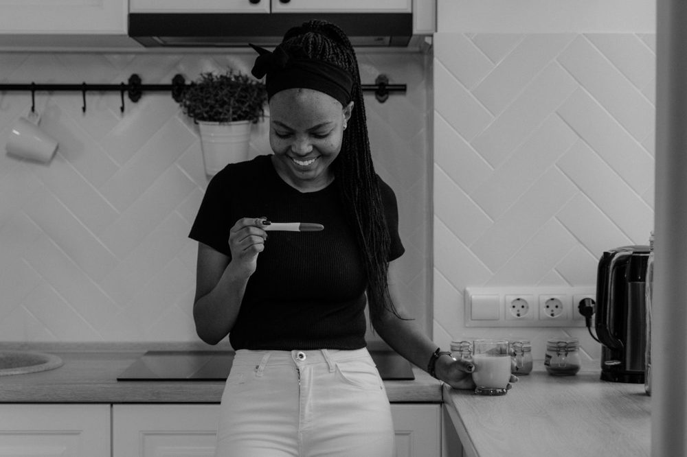 Smiling woman looking at a pregnancy test in her kitchen